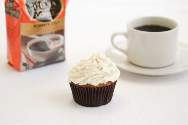 photo of a cupcake with a mug of coffee in the background