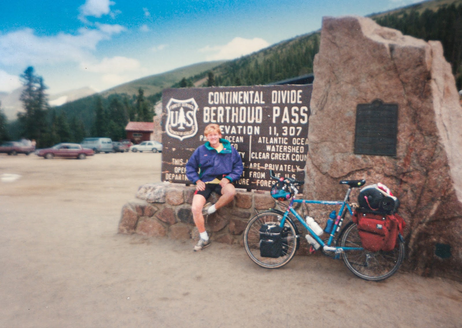 Bicycle and cyclist at the Continental Divide sign that says: Berthoud Pass Elevation 11,307