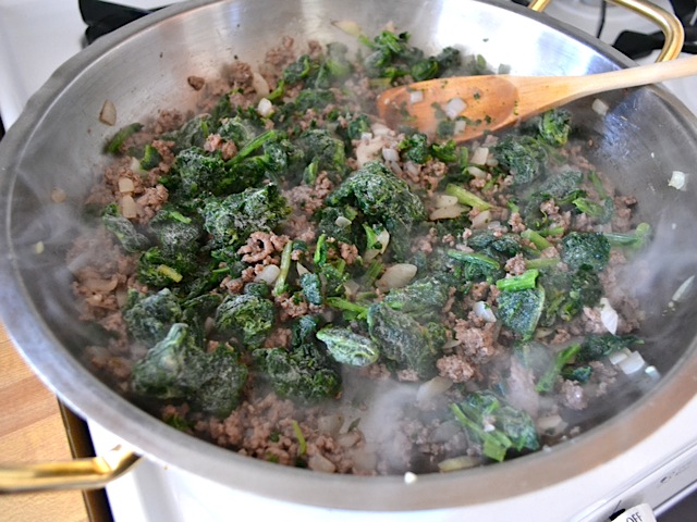 spinach added to meat mixture in pan 