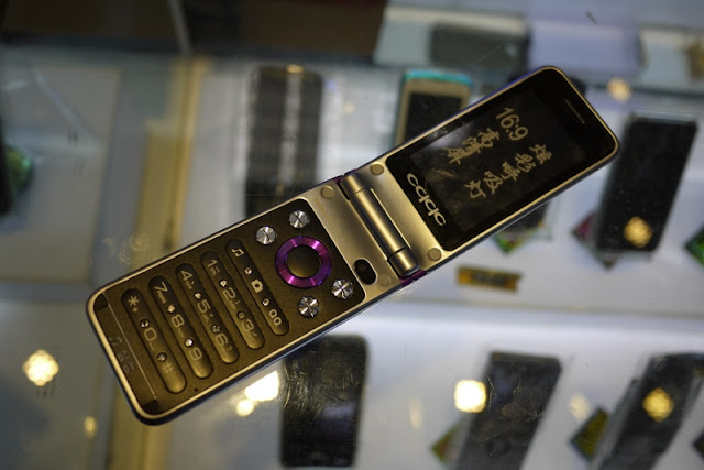 open flip phone in China with fake diamonds in the keypad, a QQ button, and an altered Oppo logo