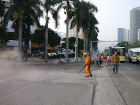 man using a blower to move gravel and creating a large dust cloud on a street in Zhuhai