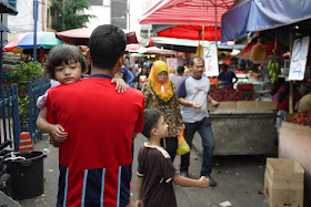 sleepy girl being carried at Bazaar Baru Chow Kit in Kuala Lumpur, Malaysia