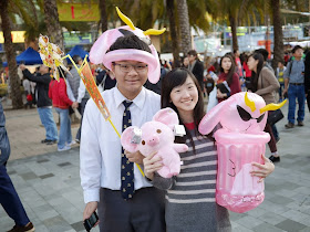 high school boy and girl holding and wearing pink inflatable items and a pink stuffed animal