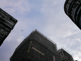 view between two buildings of a plane flying above
