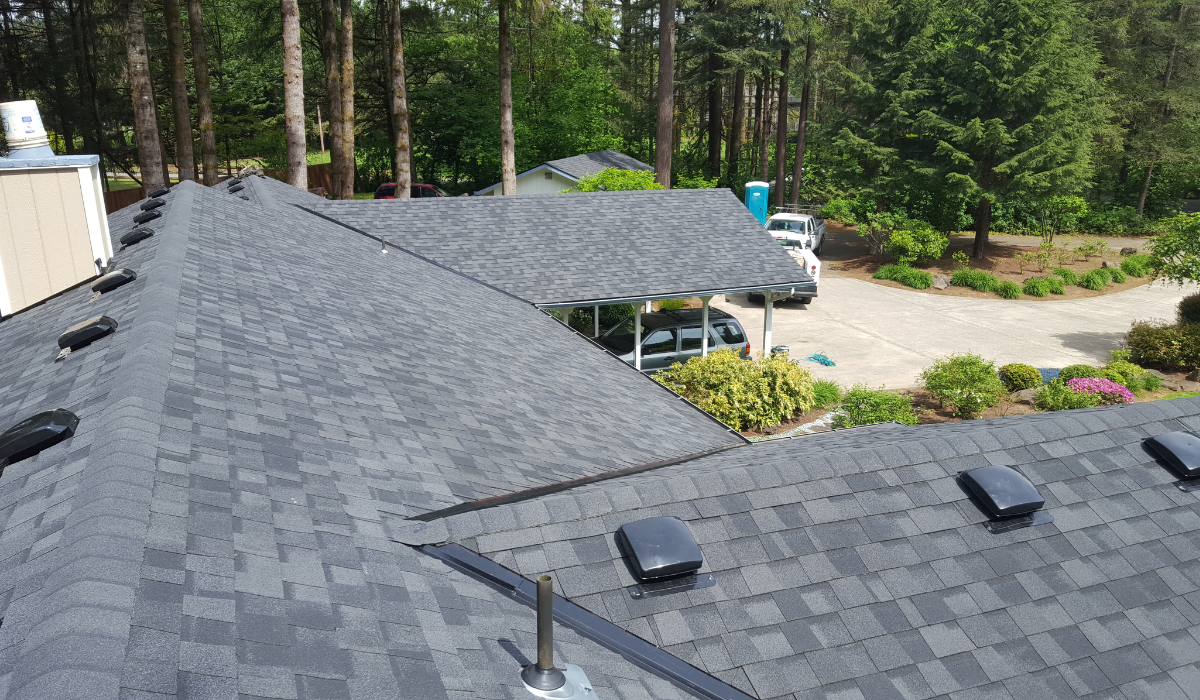 Roof repair, worker with white gloves replacing gray tiles or shingles on  house with blue sky