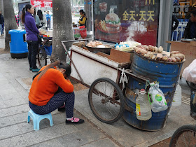 Food vendor resting in Zhuhai near an advertisement for McDonald's