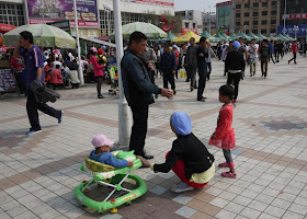 man handing a canned drink to a little girl at Nanmen Square in Yinchuan, Ningxia, China