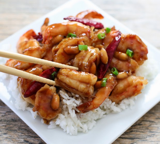 a close-up of chopsticks holding a kung pao shrimp