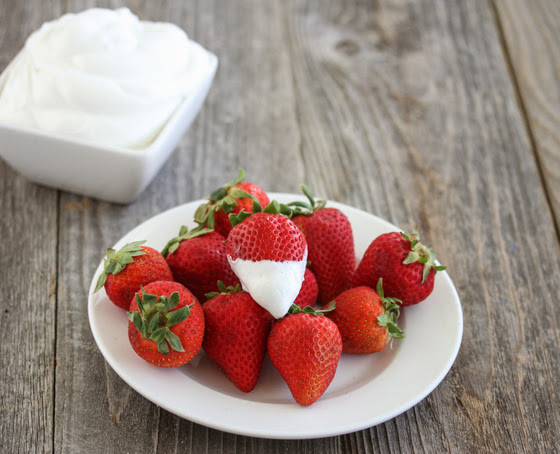 photo of a plate of strawberries with one dipped in coconut whipped cream