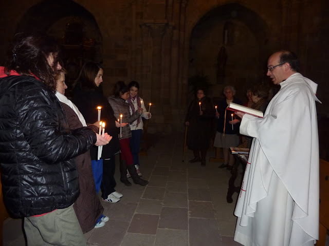 El párroco oficia la misa frente a los feligreses, que asisten dispuestos en círculo y portando una vela en la mano cada uno