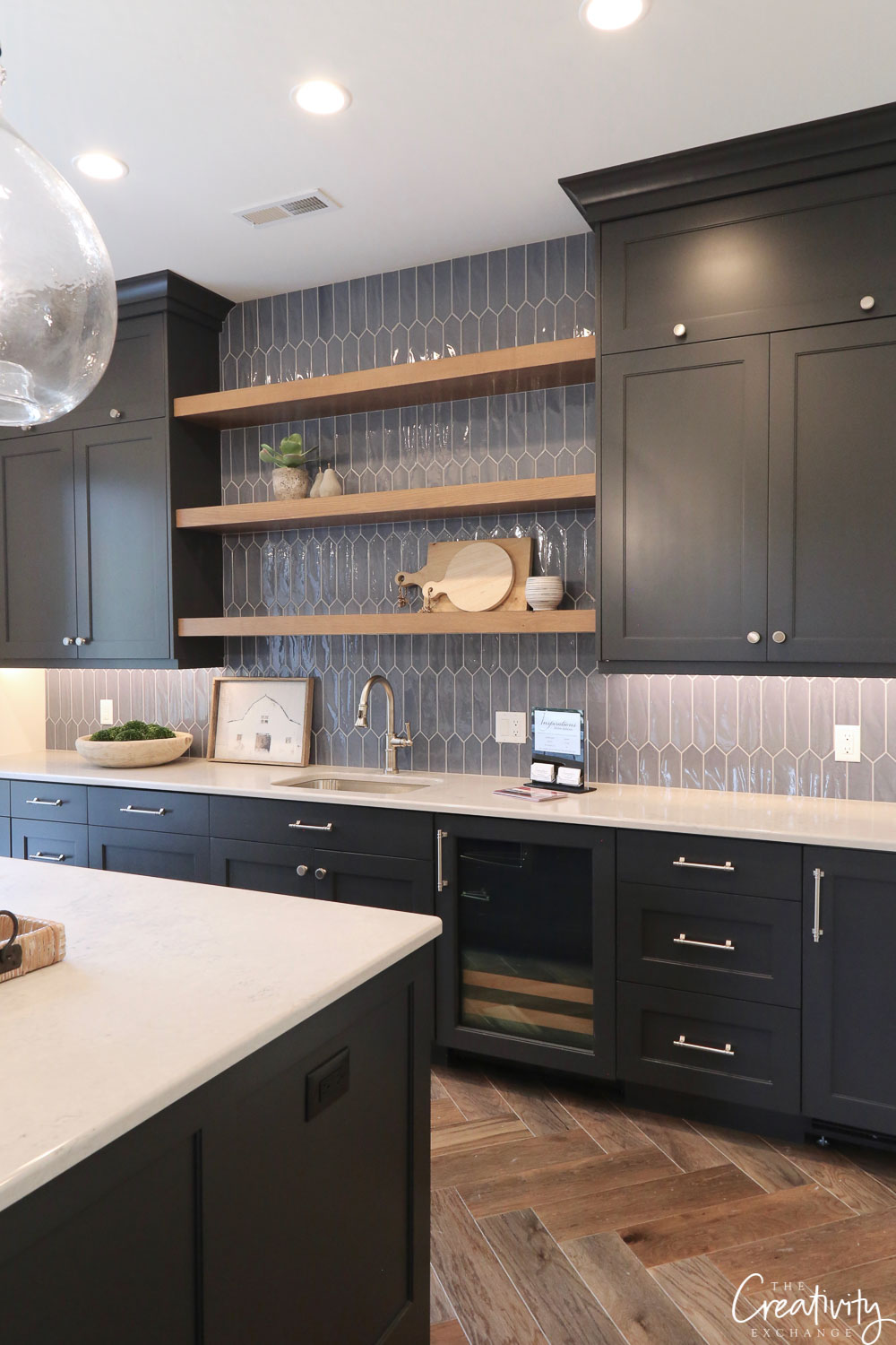 large contemporary kitchen with black shaker cabinets, chrome cabinet pulls and knobs, open shelving, white countertops and glossy blue backsplash