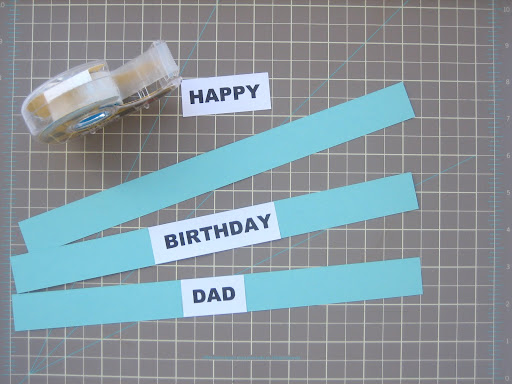 Use double sided tape to adhere the text to the paper strips.