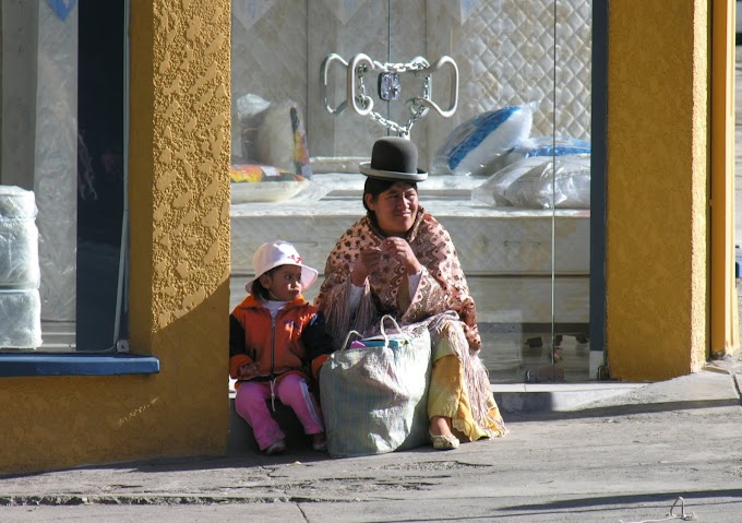 Mujer de pollera y su hija pequeña descansando