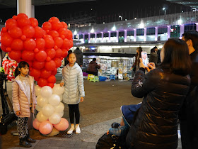 two girls posing for a photo next to a heart balloon sculpture