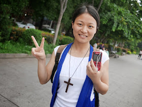 young woman holding a small electronic dictionary and wear a necklace with a cross