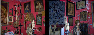 A red-walled room filled with crucifixes, statues of Jesus, and candles