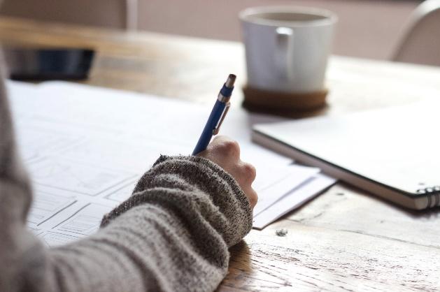 A person writing on a piece of paper

Description automatically generated with medium confidence