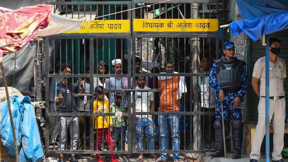 Local residents look on as a team of Rapid Action Force (RAF) patrols the area where communal violence broke during a Shobha Yatra on Hanuman Jayanti, at Jahangirpuri, on April 17, 2022 in New Delhi, India.