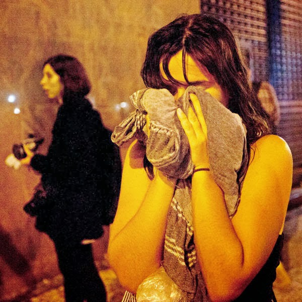 A woman covers from tear gas fired by police near the Cinelandia square after a march in support of teachers on strike in Rio de Janeiro, Brazil.