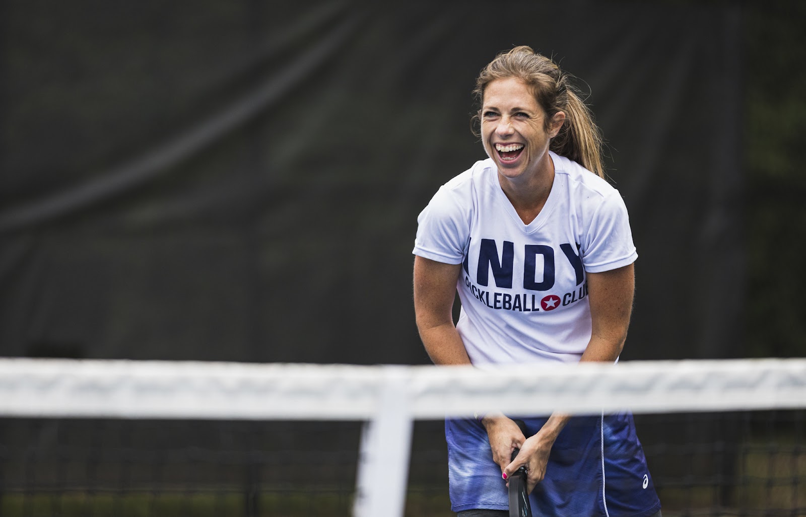 Female pickleball player laughing on the court