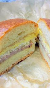 Portland Penny Diner's breakfast sandwich of PDXWT duck bologna, sauerkraut, coffee mayo, egg, american cheese, on the soft, buttery, and fresh parker house roll.