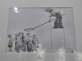 Security (安全) by Fang Tang (方唐) depicting the Statue of Liberty waving a metal detector over people