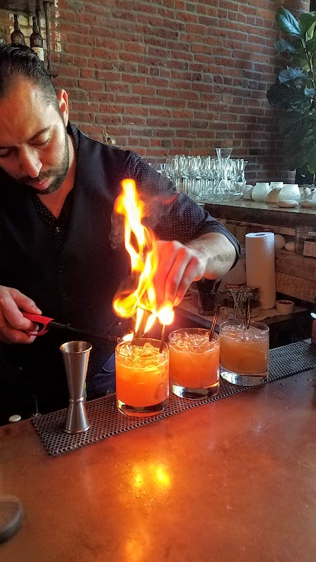 The Fogo Laranja (Orange Fire) cocktail with Leblon cachaca, orange juice, lime, cane syrup, Amardo di angostura, and flamed orange from LeChon