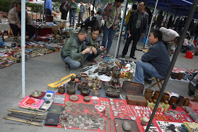 men squatting while examining a sword for sale outside Tianxinge Antique City in Changsha, China
