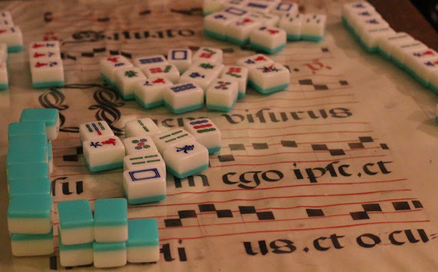 mah jongg tiles spread on a sheet of medieval song manuscript