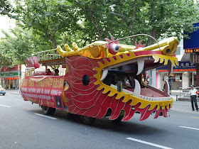 a vehicle (dragonmobile) decorated to look like a dragon driving down a street in Shanghai