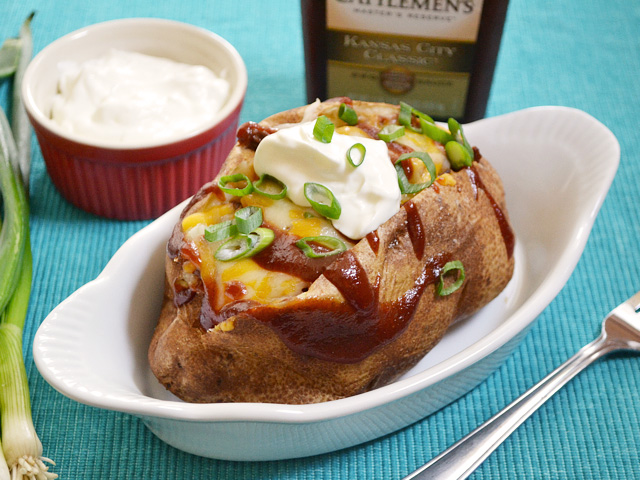 BBQ Beef Stuffed Potatoe in dish with fork and a side of sour cream on the side 