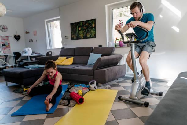 Sporty couple training at home every day Sporty couple training at home every day air bikes in living room stock pictures, royalty-free photos & images
