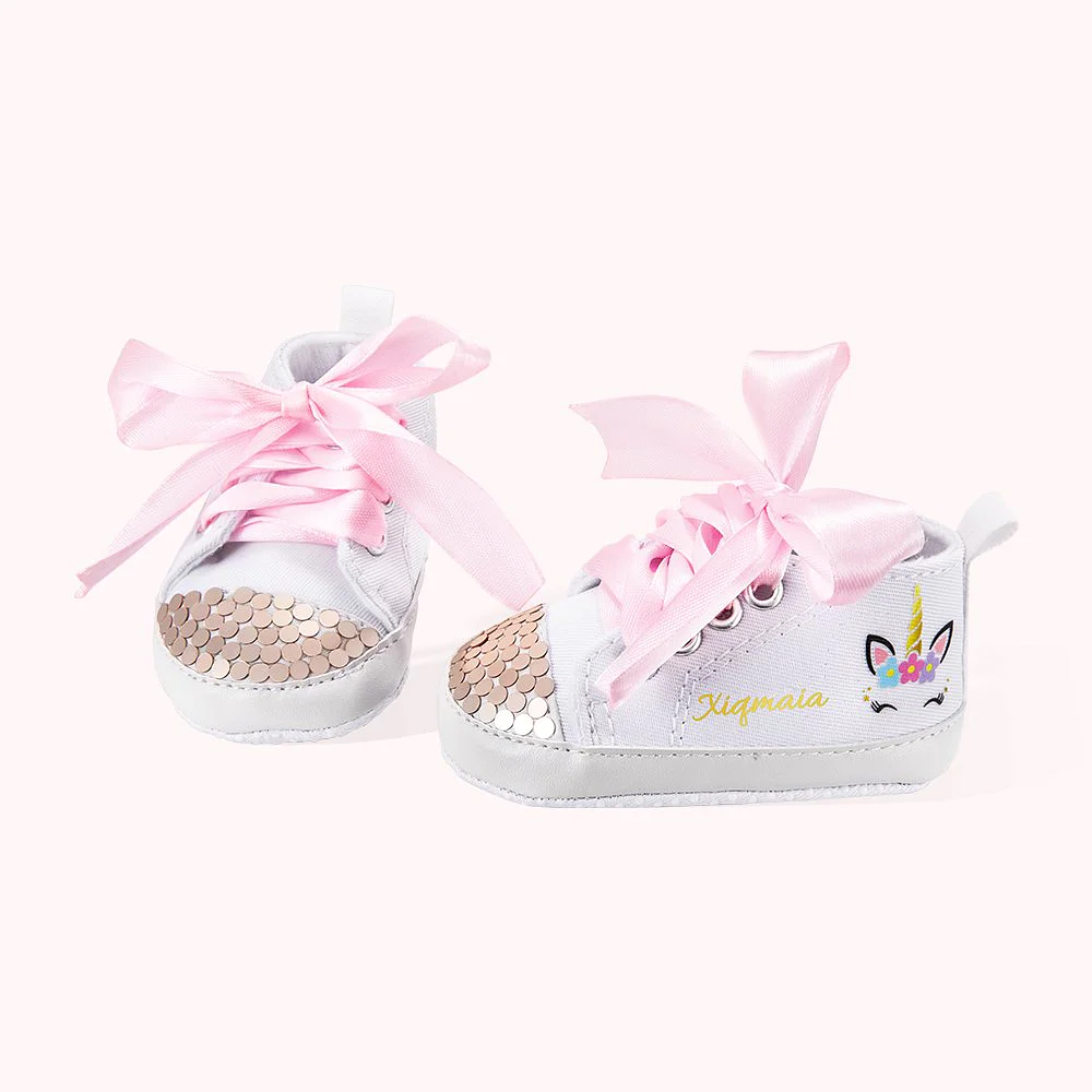 Chaussures de marche pour bébé, avec lacets roses, tête de licorne au talon et personnalisées sur la partie extérieure de chaque chaussure.