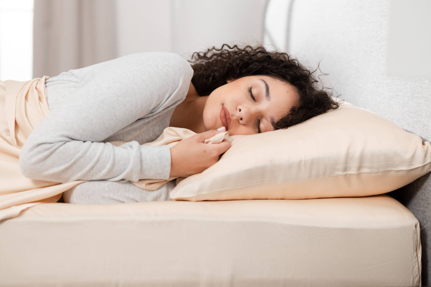 A woman sleeping on a set of Hush Iced 2.0 Bamboo sheets in latte color.