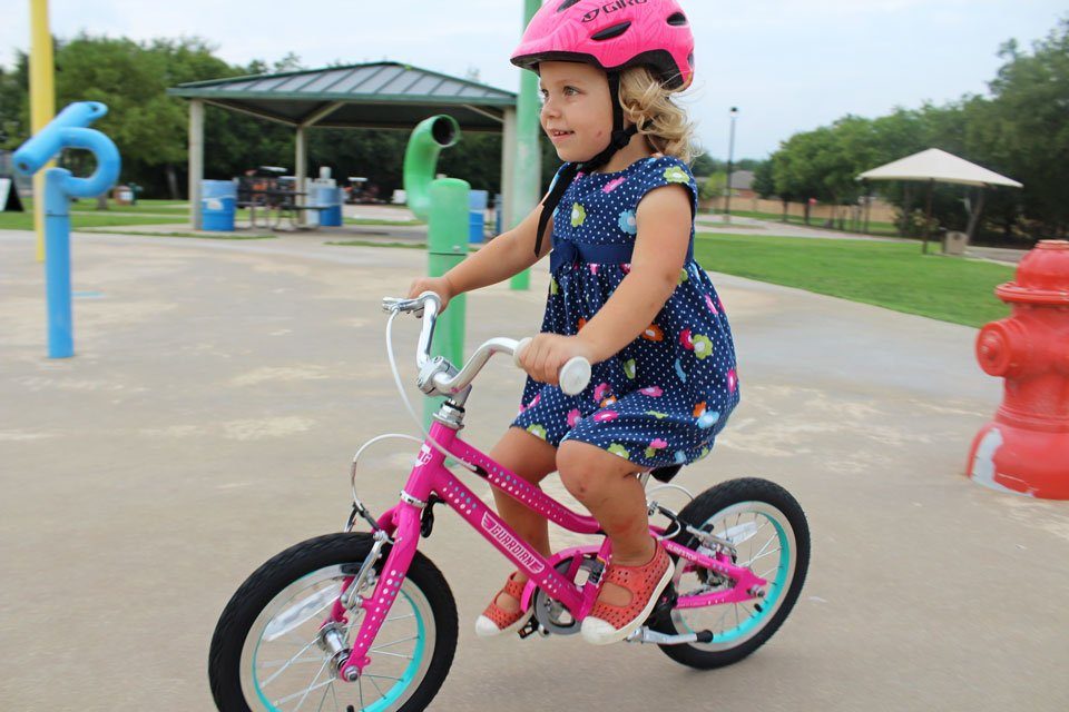 3 year old riding Guardian Ethos 14 inch girls bike through splash pad