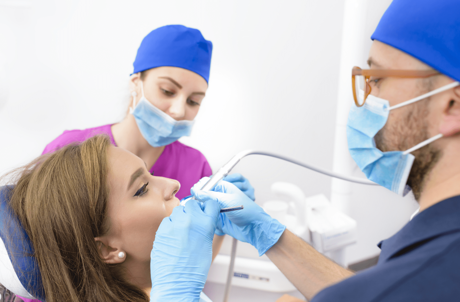 A male dentist and female dental hygienist preparing to do a root canal on the patients teeth