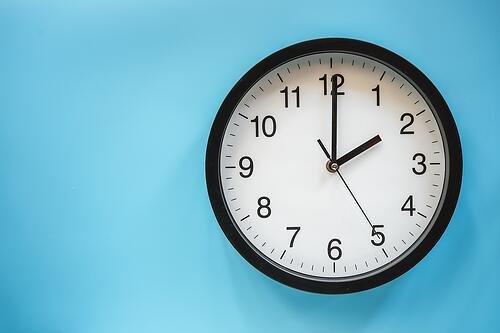 classic-black-and-white-analog-clock-on-blue-background-at-two-o-clock-with-copy-space