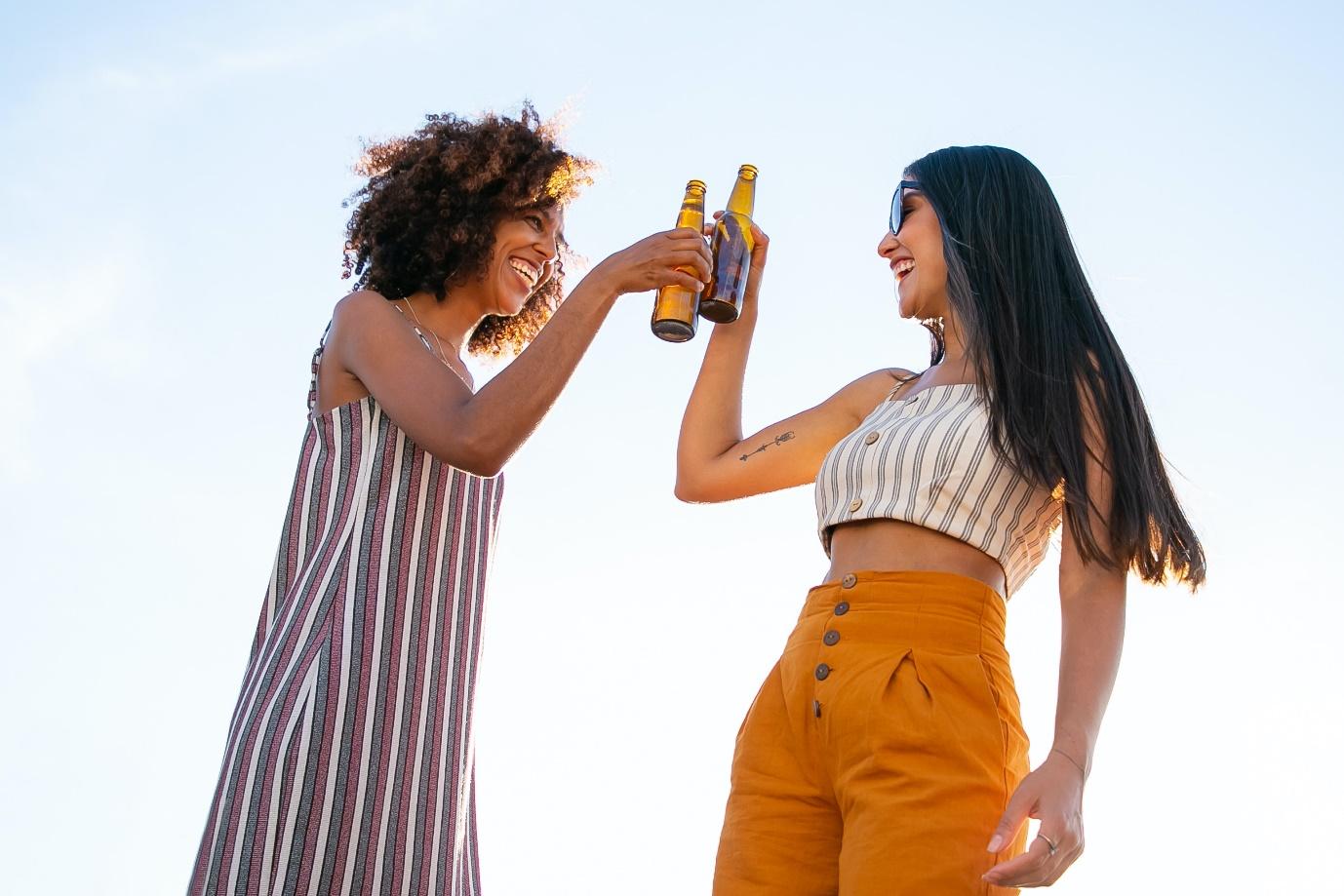 Two women holding a bottle of beer.