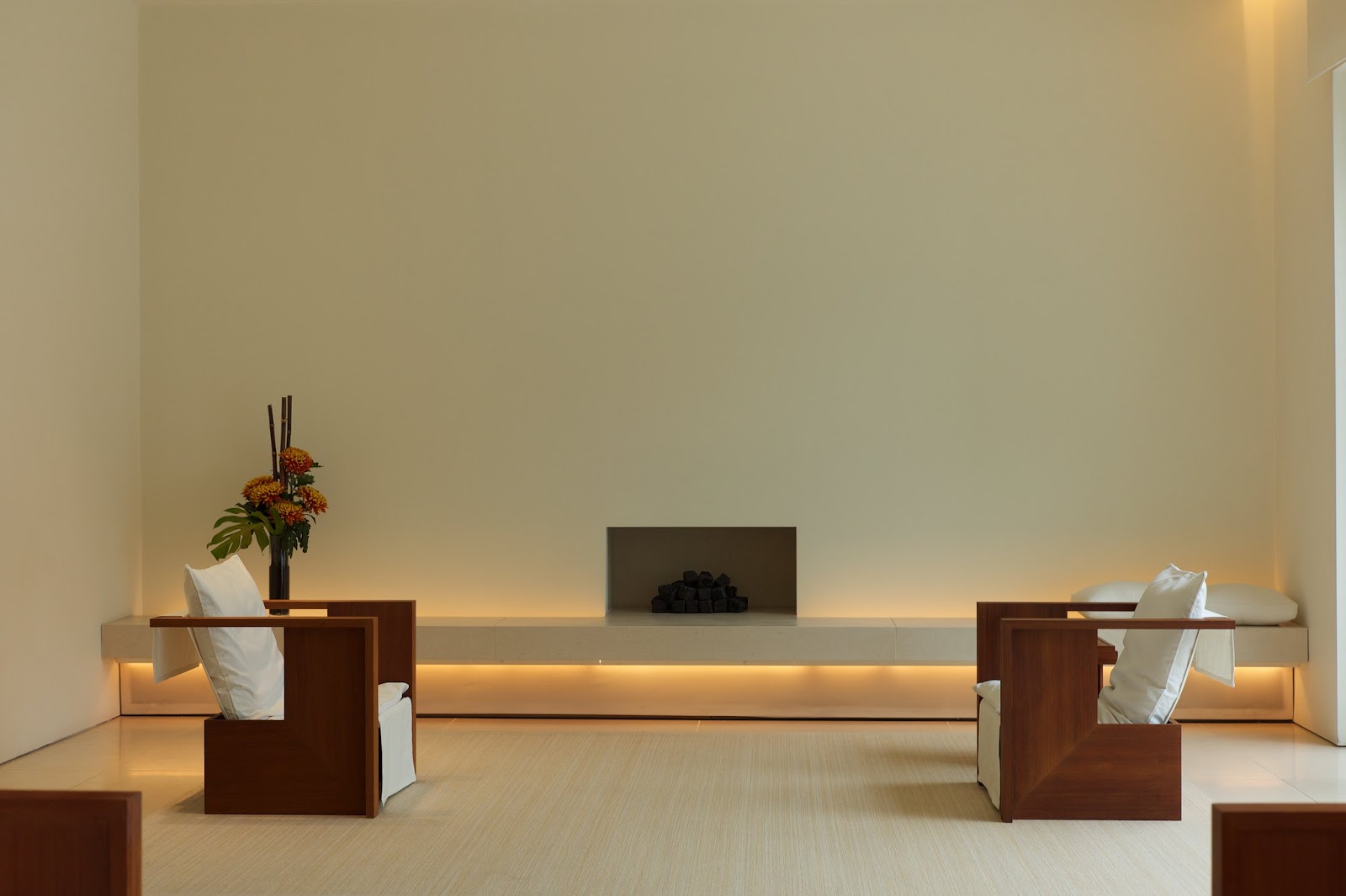 A very simplistic, clean and modern room interior featuring a small fireplace and two armchairs.