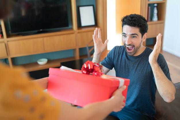 Portrait of a woman surprising her boyfriend with a present. celebration and valentine's day concept. Free Photo