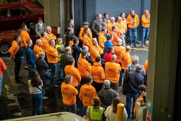 A group of people in orange shirts  Description automatically generated with medium confidence