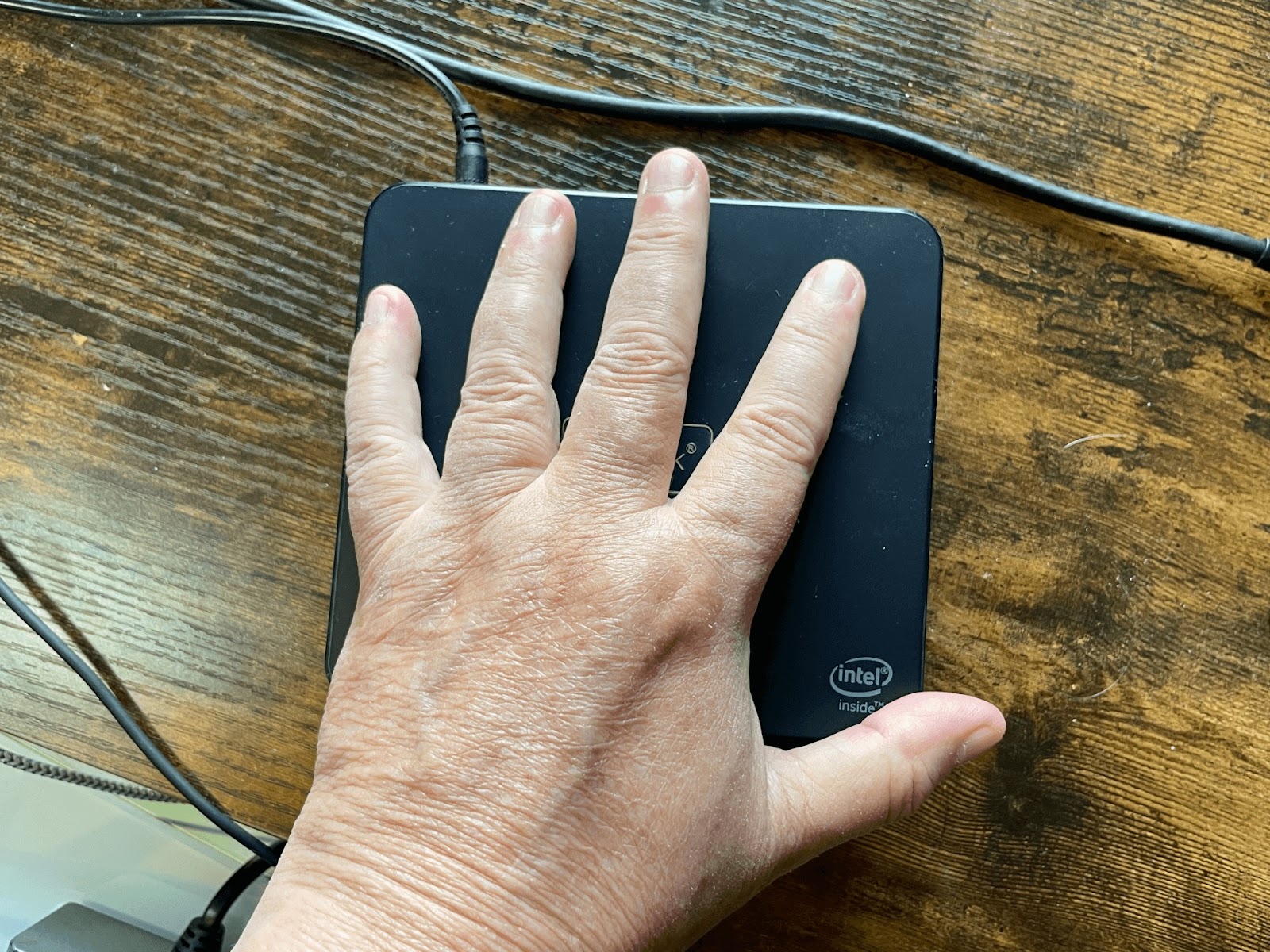 My hand resting on top of a mini pc.