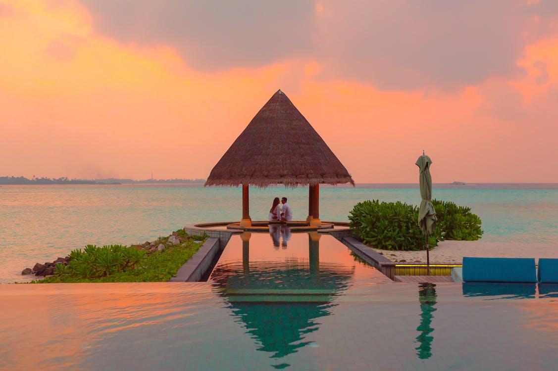 Couple Under Hut Beside Sea and Infinity Pool