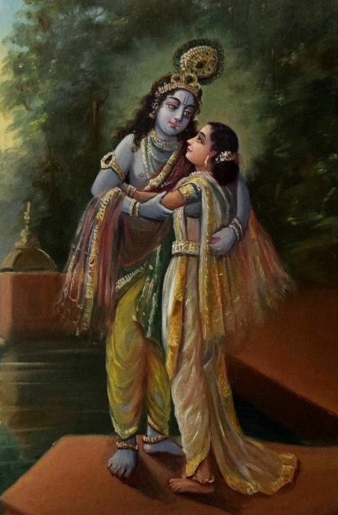 The image shows Radha and Krishna embracing and both wearing yellow clothing. 