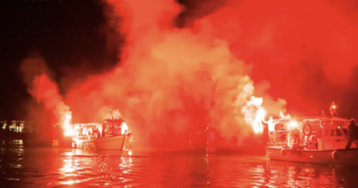 Image of burning boats on the water. 