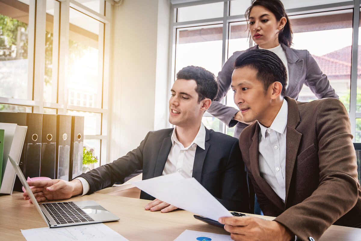 3 employees looking at a laptop