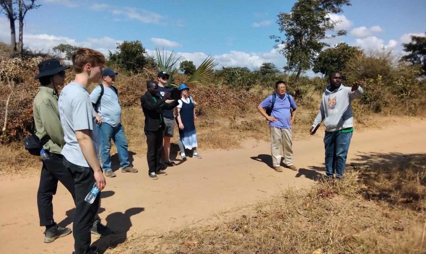 A group of people walking on a dirt road

Description automatically generated