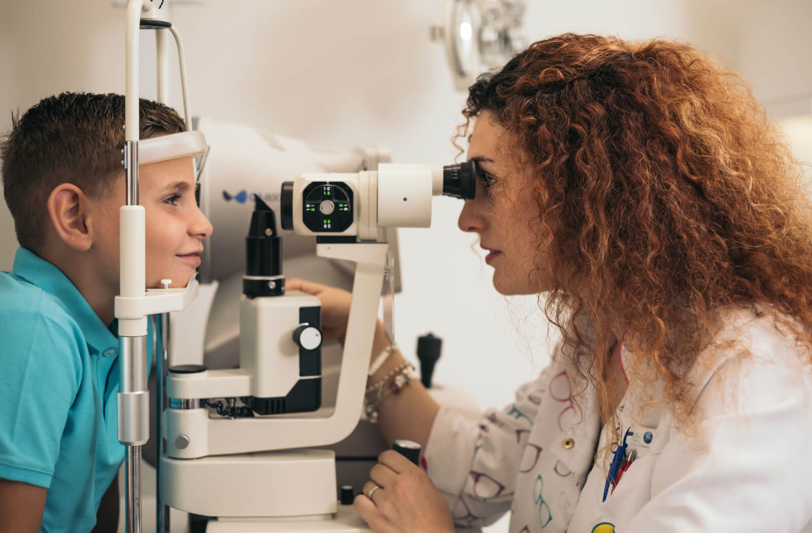 An optometrist  conducting an eye exam on a child using a device that tests his vision