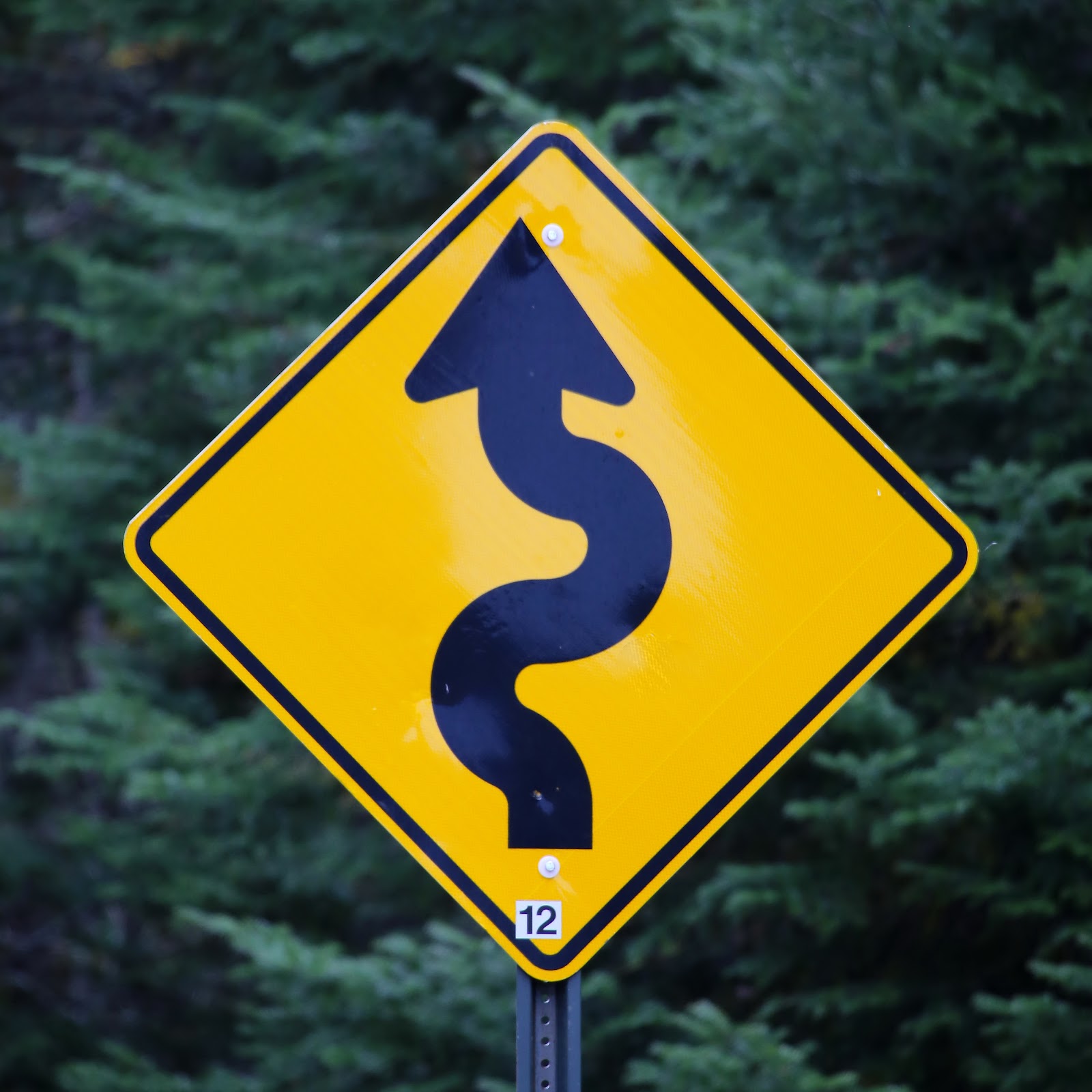 Picture of a yellow road sign indicating many turns ahead