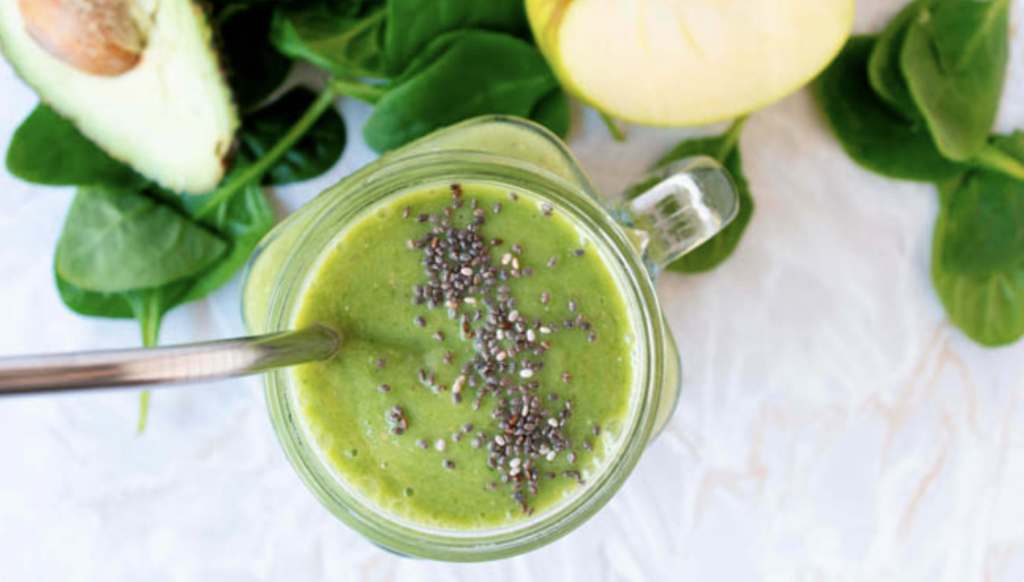 spinach and pear smoothie with chia seeds in a glass with a straw